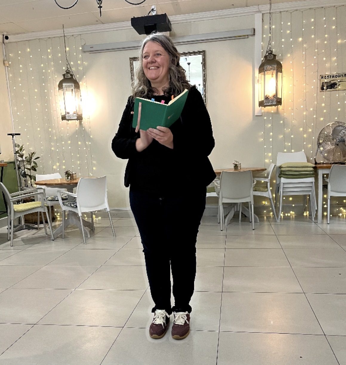 Michelle smiling, holding a green notebook full of marked pages